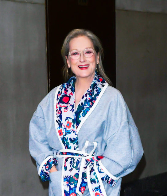 Meryl Streep in a long blue coat with red heels.