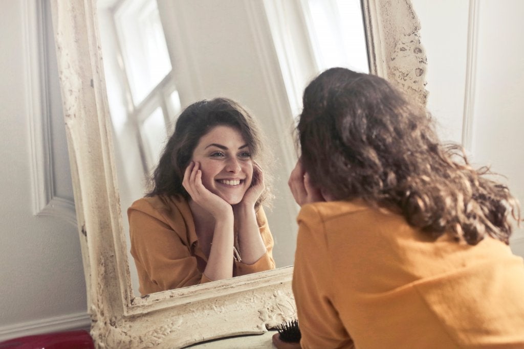Woman looking at her reflection in the mirror while smiling